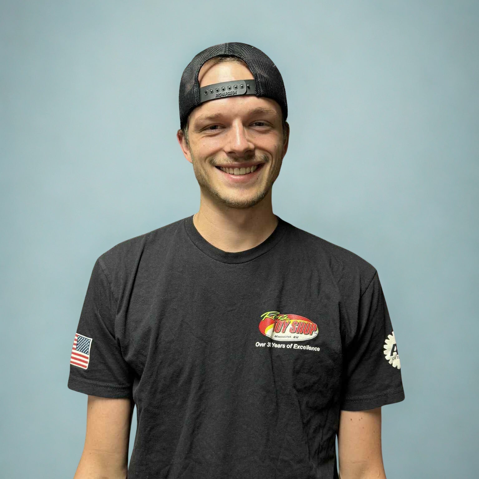 Man wearing a black t-shirt with a logo and text on a gray background