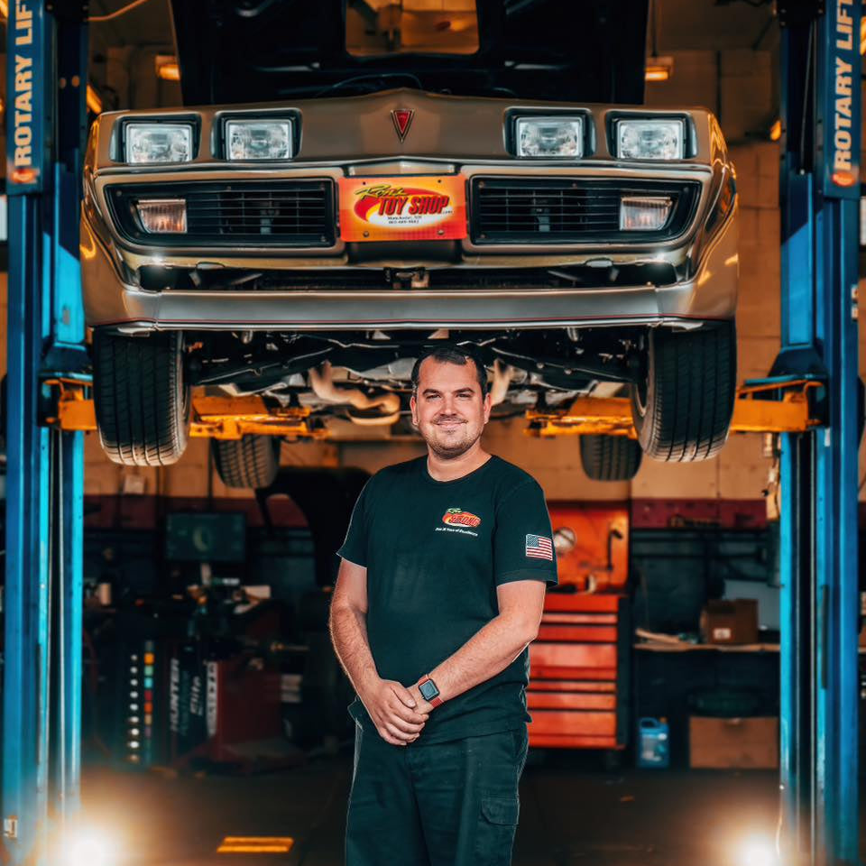 Man standing in a garage with a car on a lift