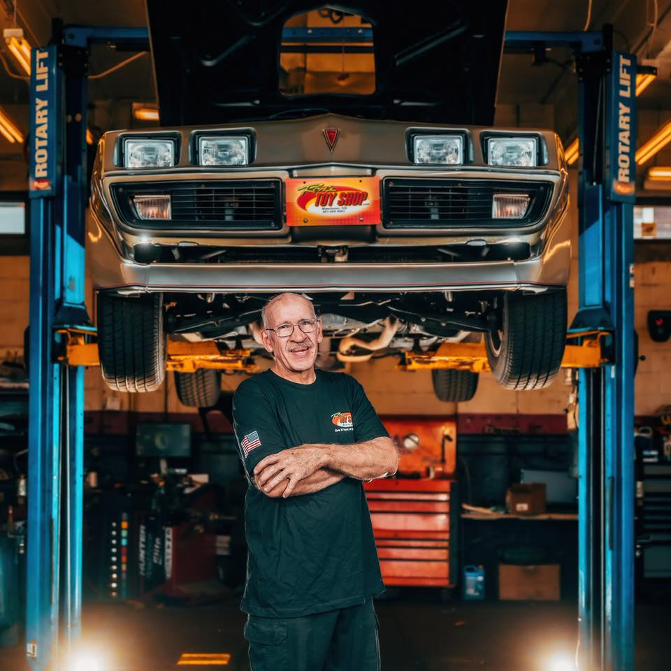 Mechanic standing in a garage with a car on a lift