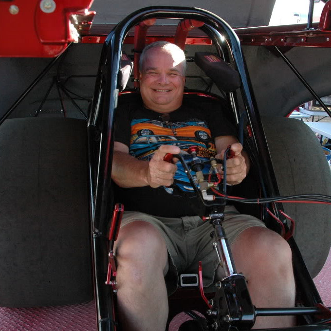 Man sitting inside a small racecar with visible controls